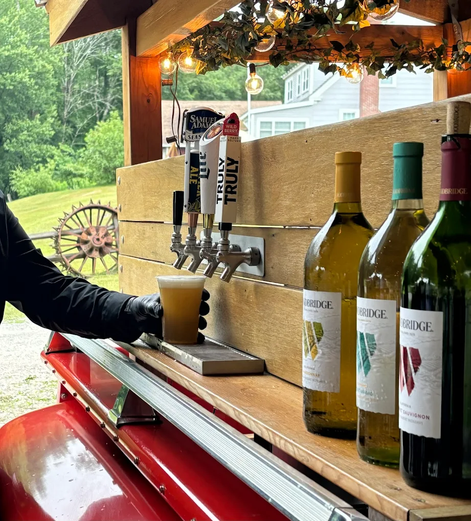 Bartender pouring draft beer from vintage tap truck with wine bottles